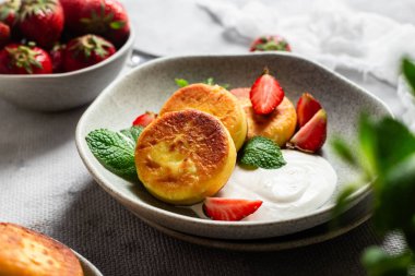 Syrniki Cheesecakes krem soslu süzme peynirli krep, çilek ve nane şekeri tabakta. Kahvaltı.