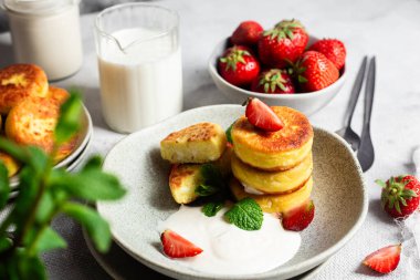 Syrniki Cheesecakes krem soslu süzme peynirli krep, çilek ve nane şekeri tabakta. Kahvaltı.