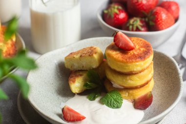 Syrniki Cheesecakes krem soslu süzme peynirli krep, çilek ve nane şekeri tabakta. Kahvaltı.