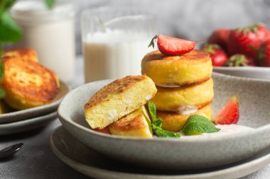 Syrniki Cheesecakes krem soslu süzme peynirli krep, çilek ve nane şekeri tabakta. Kahvaltı.