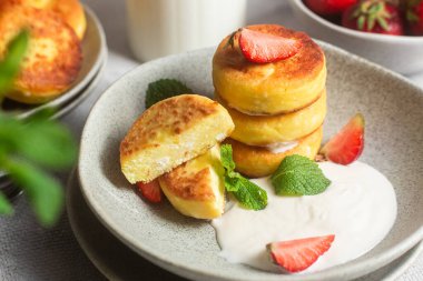 Syrniki Cheesecakes krem soslu süzme peynirli krep, çilek ve nane şekeri tabakta. Kahvaltı.