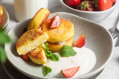 Syrniki Cheesecakes krem soslu süzme peynirli krep, çilek ve nane şekeri tabakta. Kahvaltı.