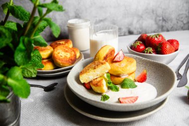 Syrniki Cheesecakes krem soslu süzme peynirli krep, çilek ve nane şekeri tabakta. Kahvaltı.