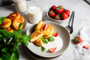 Syrniki Cheesecakes krem soslu süzme peynirli krep, çilek ve nane şekeri tabakta. Kahvaltı.