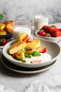 Syrniki Cheesecakes krem soslu süzme peynirli krep, çilek ve nane şekeri tabakta. Kahvaltı.