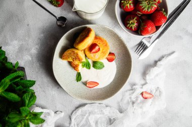 Syrniki Cheesecakes krem soslu süzme peynirli krep, çilek ve nane şekeri tabakta. Kahvaltı.