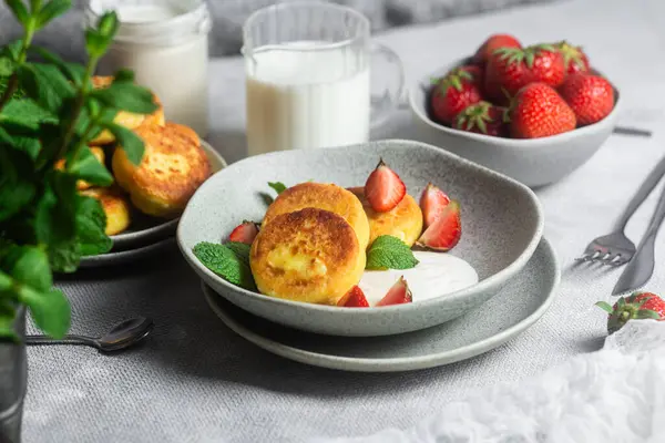 Syrniki Cheesecakes krem soslu süzme peynirli krep, çilek ve nane şekeri tabakta. Kahvaltı.