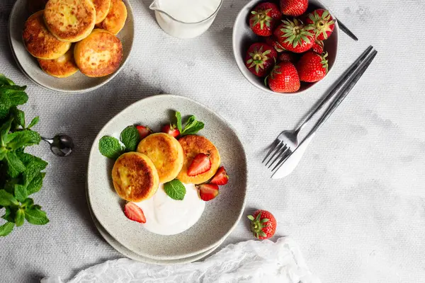 Syrniki Cheesecakes krem soslu süzme peynirli krep, çilek ve nane şekeri tabakta. Kahvaltı.