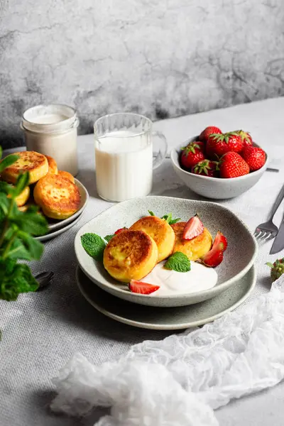 Syrniki Cheesecakes krem soslu süzme peynirli krep, çilek ve nane şekeri tabakta. Kahvaltı.