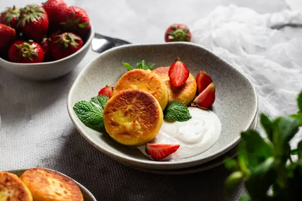 Syrniki Cheesecakes krem soslu süzme peynirli krep, çilek ve nane şekeri tabakta. Kahvaltı.