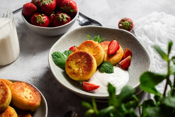 Syrniki Cheesecakes krem soslu süzme peynirli krep, çilek ve nane şekeri tabakta. Kahvaltı.