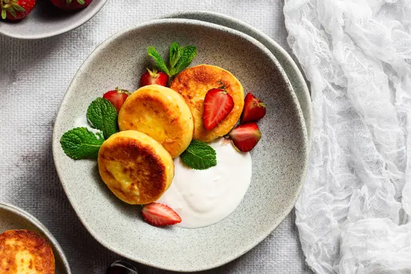 Syrniki Cheesecakes krem soslu süzme peynirli krep, çilek ve nane şekeri tabakta. Kahvaltı.