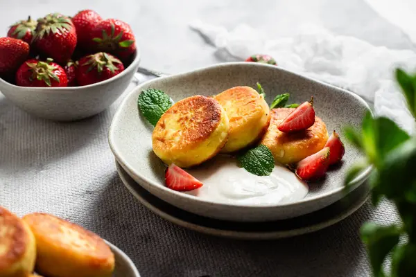 Syrniki Cheesecakes krem soslu süzme peynirli krep, çilek ve nane şekeri tabakta. Kahvaltı.