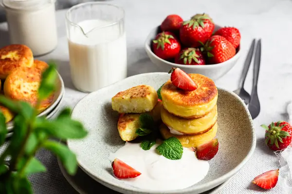 Syrniki Cheesecakes krem soslu süzme peynirli krep, çilek ve nane şekeri tabakta. Kahvaltı.