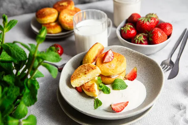 Syrniki Cheesecakes krem soslu süzme peynirli krep, çilek ve nane şekeri tabakta. Kahvaltı.