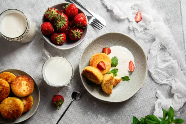 Syrniki Cheesecakes krem soslu süzme peynirli krep, çilek ve nane şekeri tabakta. Kahvaltı.