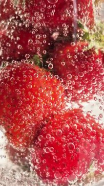 Yakından bakınca köpüklü suda olgun çilekler. Su ve çilek kabarcıkları