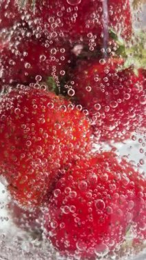 Yakından bakınca köpüklü suda olgun çilekler. Su ve çilek kabarcıkları