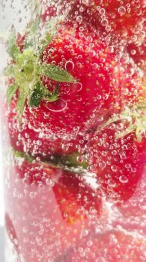 Yakından bakınca köpüklü suda olgun çilekler. Su ve çilek kabarcıkları