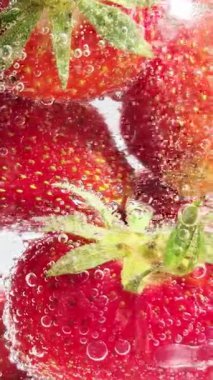 Yakından bakınca köpüklü suda olgun çilekler. Su ve çilek kabarcıkları