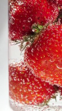 Yakından bakınca köpüklü suda olgun çilekler. Su ve çilek kabarcıkları