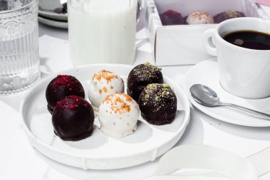 Beyaz tabakta el yapımı yuvarlak çikolatalı şekerler. Şekersiz çikolata. Sağlıklı tatlı.