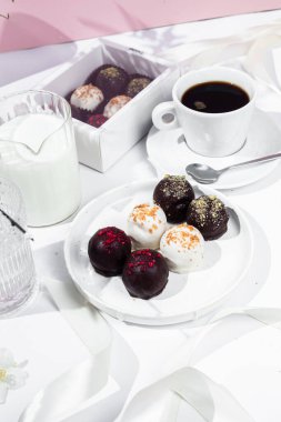 Beyaz tabakta el yapımı yuvarlak çikolatalı şekerler. Şekersiz çikolata. Sağlıklı tatlı.