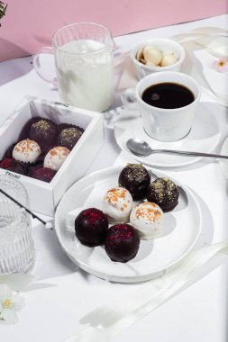 Beyaz tabakta el yapımı yuvarlak çikolatalı şekerler. Şekersiz çikolata. Sağlıklı tatlı.