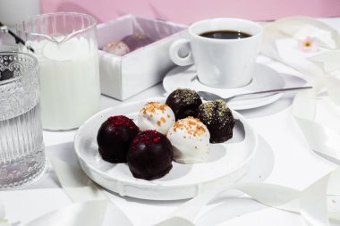 Beyaz tabakta el yapımı yuvarlak çikolatalı şekerler. Şekersiz çikolata. Sağlıklı tatlı.