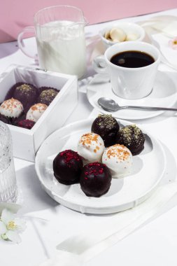 Beyaz tabakta el yapımı yuvarlak çikolatalı şekerler. Şekersiz çikolata. Sağlıklı tatlı.