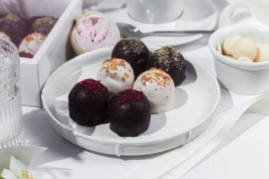 Beyaz tabakta el yapımı yuvarlak çikolatalı şekerler. Şekersiz çikolata. Sağlıklı tatlı.