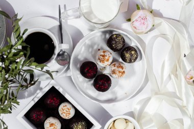 Beyaz tabakta el yapımı yuvarlak çikolatalı şekerler. Şekersiz çikolata. Sağlıklı tatlı.