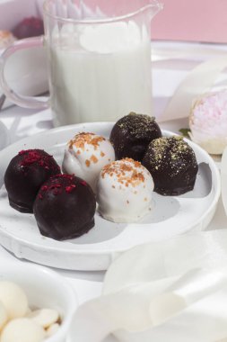 Beyaz tabakta el yapımı yuvarlak çikolatalı şekerler. Şekersiz çikolata. Sağlıklı tatlı.