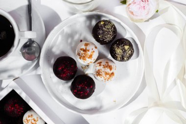 Beyaz tabakta el yapımı yuvarlak çikolatalı şekerler. Şekersiz çikolata. Sağlıklı tatlı.