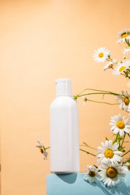 Papatya çiçekli beyaz bir şişe cilt bakımı.