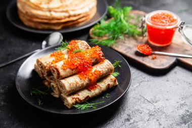 Masadaki siyah tabakta kırmızı havyarla nefis bir blini. İnce krepler. Karnaval