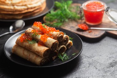 Masadaki siyah tabakta kırmızı havyarla nefis bir blini. İnce krepler. Karnaval