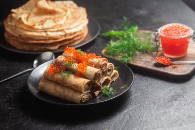 Masadaki siyah tabakta kırmızı havyarla nefis bir blini. İnce krepler. Karnaval