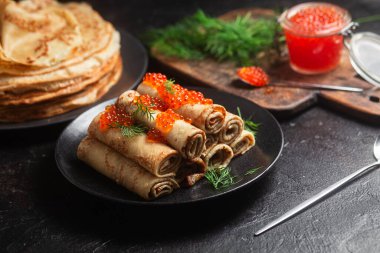 Masadaki siyah tabakta kırmızı havyarla nefis bir blini. İnce krepler. Karnaval