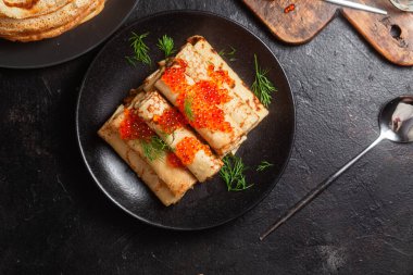 Masadaki siyah tabakta kırmızı havyarla nefis bir blini. İnce krepler. Karnaval