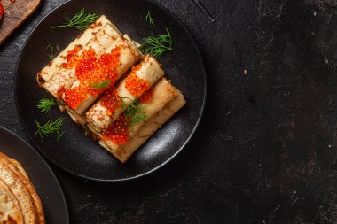 Masadaki siyah tabakta kırmızı havyarla nefis bir blini. İnce krepler. Karnaval