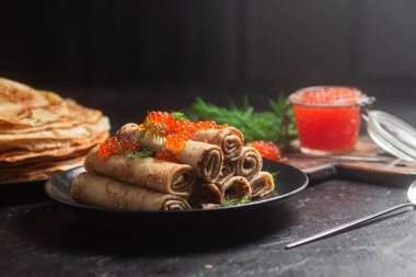 Masadaki siyah tabakta kırmızı havyarla nefis bir blini. İnce krepler. Karnaval
