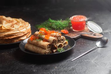 Masadaki siyah tabakta kırmızı havyarla nefis bir blini. İnce krepler. Karnaval