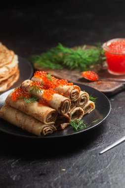 Masadaki siyah tabakta kırmızı havyarla nefis bir blini. İnce krepler. Karnaval