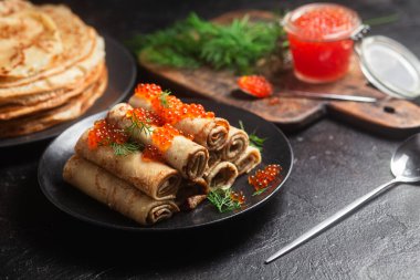 Masadaki siyah tabakta kırmızı havyarla nefis bir blini. İnce krepler. Karnaval