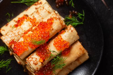 Masadaki siyah tabakta kırmızı havyarla nefis bir blini. İnce krepler. Karnaval