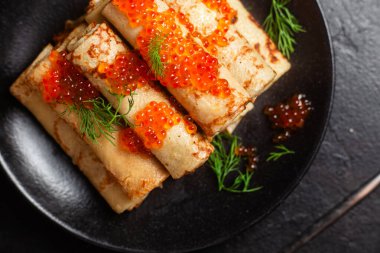 Masadaki siyah tabakta kırmızı havyarla nefis bir blini. İnce krepler. Karnaval