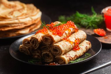 Masadaki siyah tabakta kırmızı havyarla nefis bir blini. İnce krepler. Karnaval