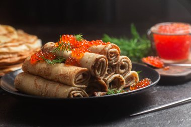 Masadaki siyah tabakta kırmızı havyarla nefis bir blini. İnce krepler. Karnaval