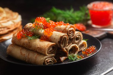 Masadaki siyah tabakta kırmızı havyarla nefis bir blini. İnce krepler. Karnaval